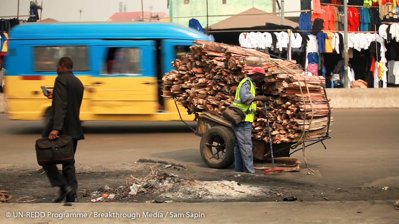 A cart carrying woodfuel in the middle of a busy city 